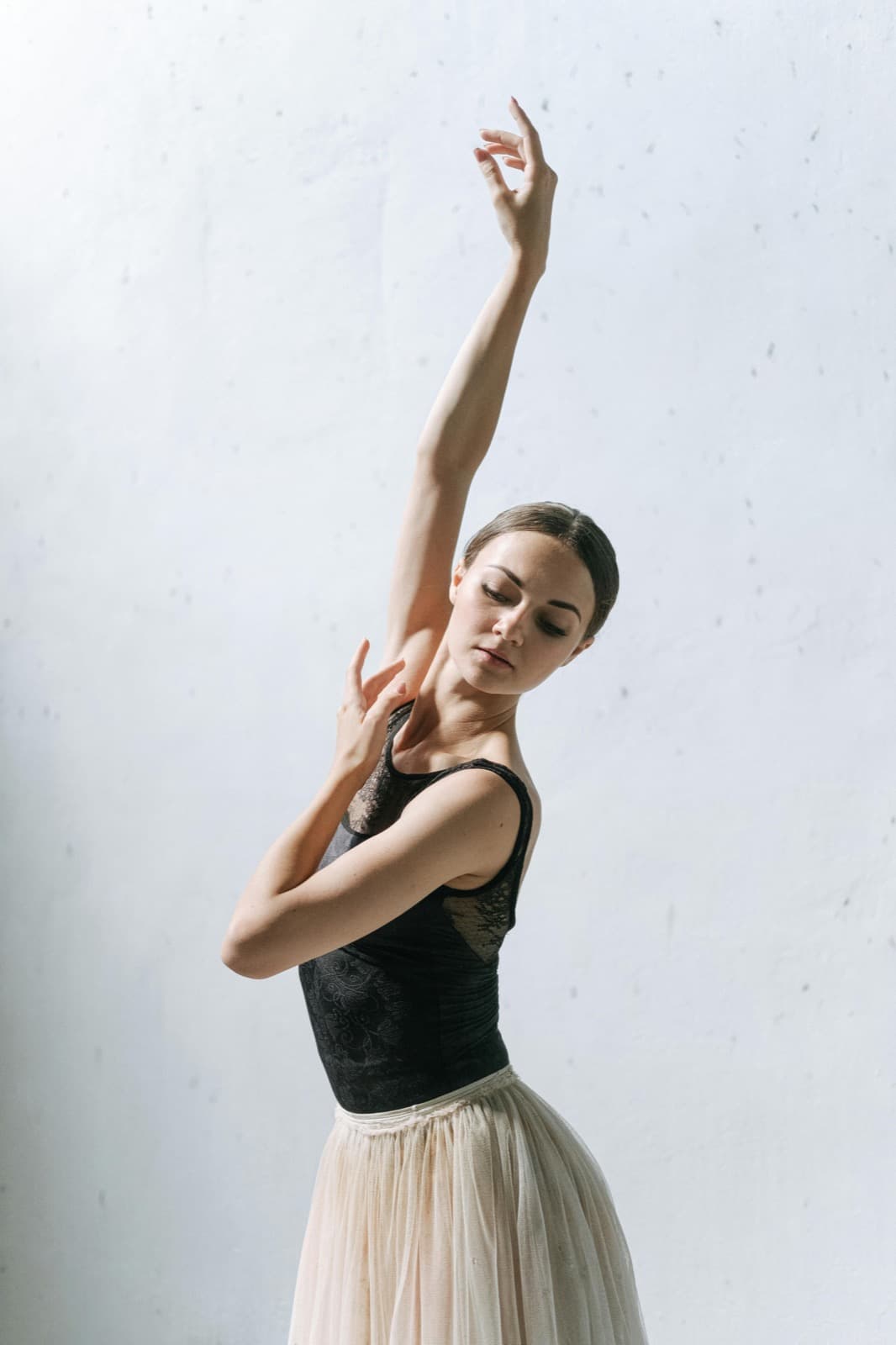 A dancer poised in the studio, arm raised, in soft natural light